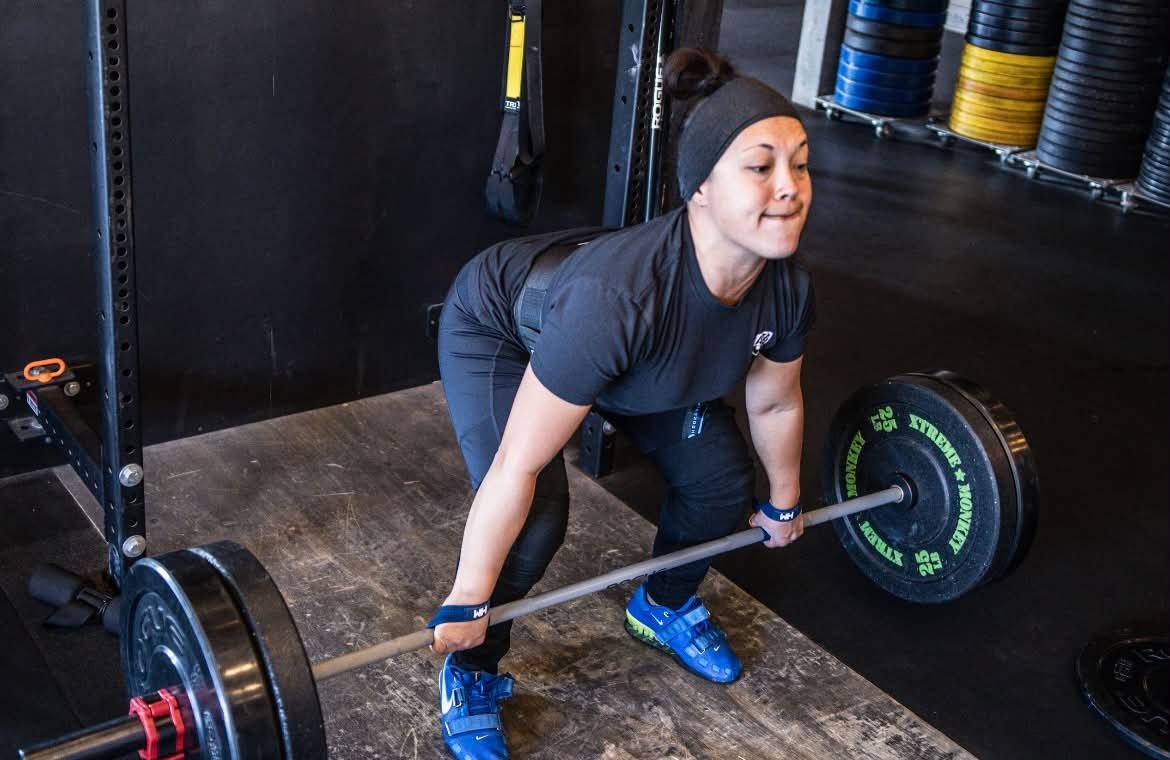 Coach JJ preparing to deadlift a loaded barbell